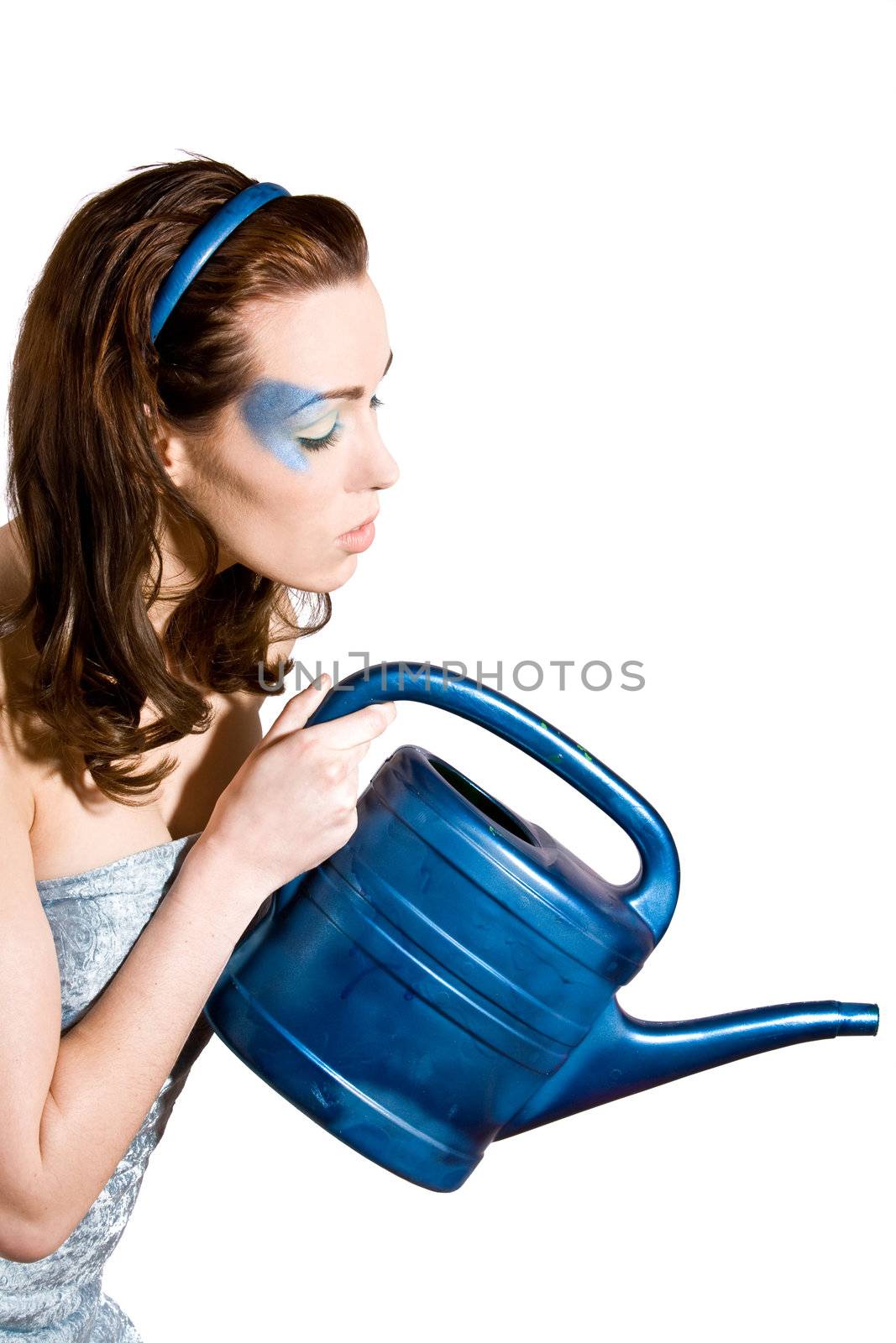 Pretty brunette with blue eyeshadow watering the plants with a blue watering can