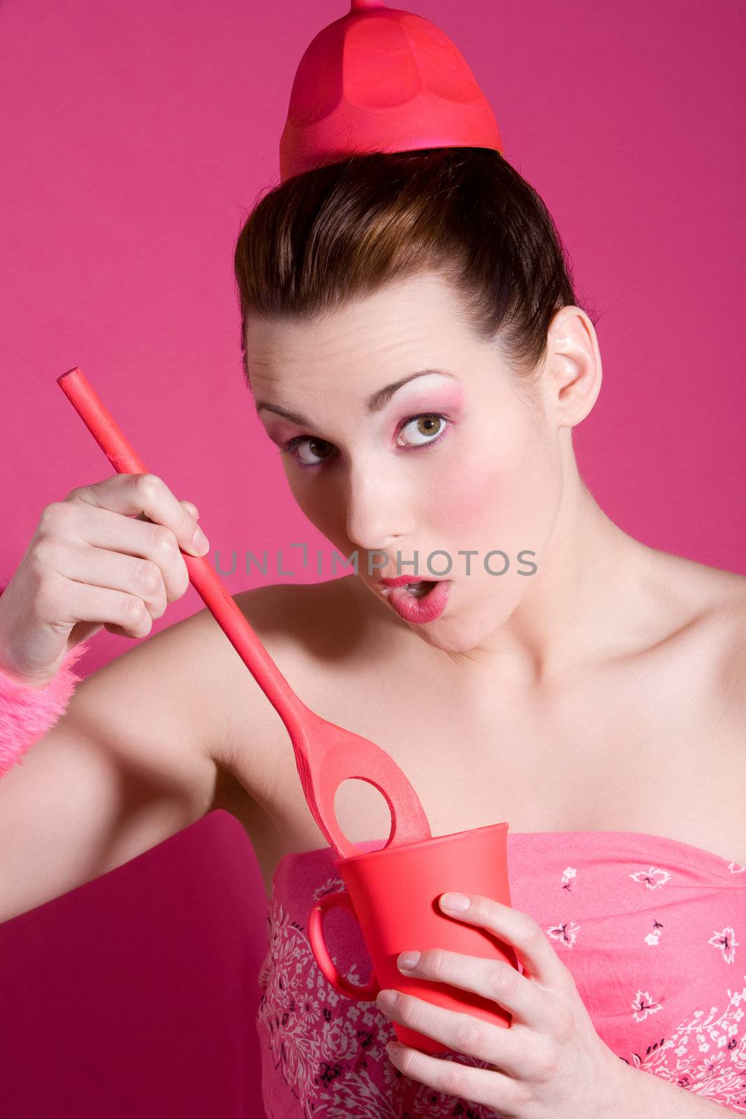 Pretty brunette with pink background, red cup and wooden spoon