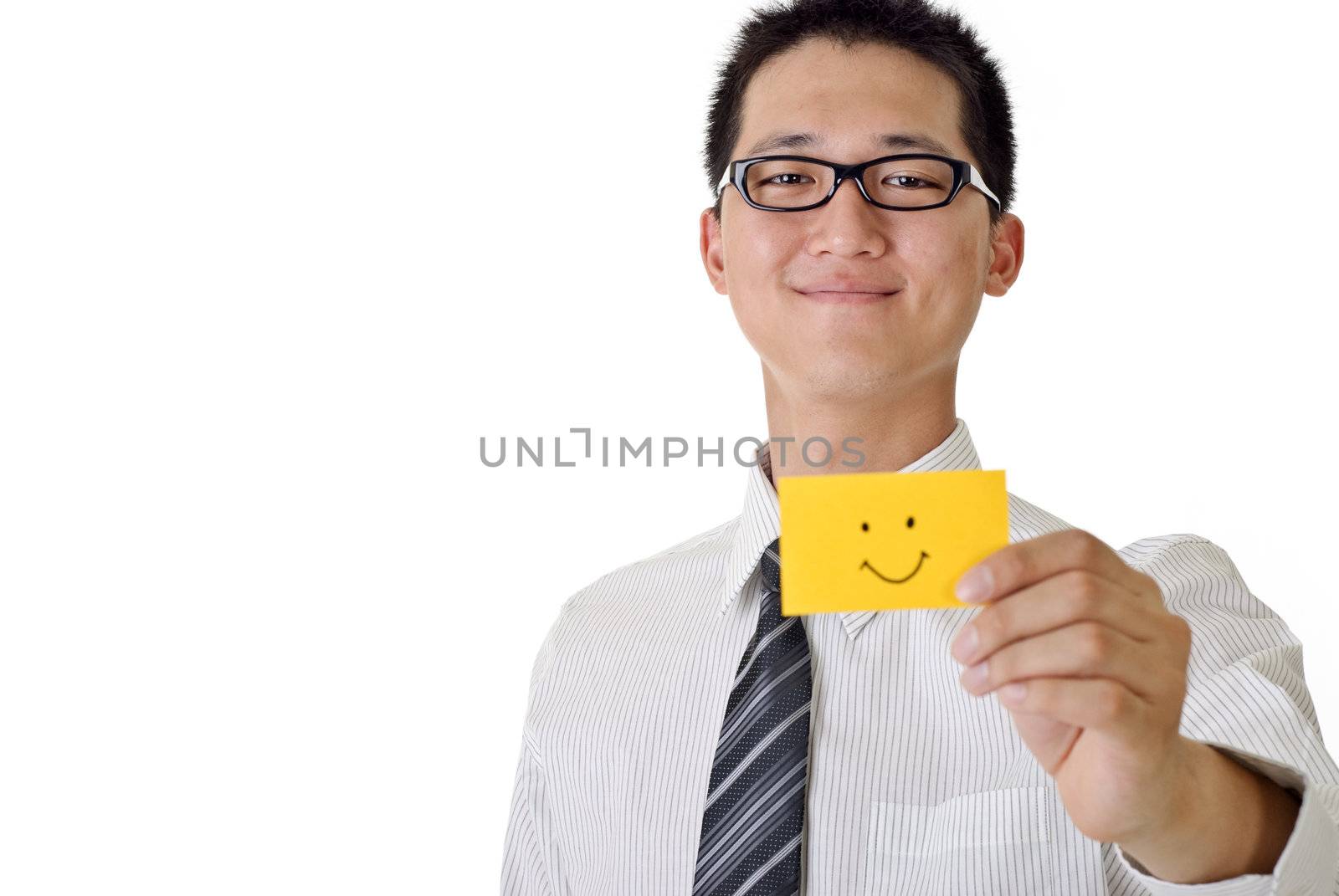 Smiling business man holding yellow card with smiling face, focus on face. Closeup portrait with white copyspace.