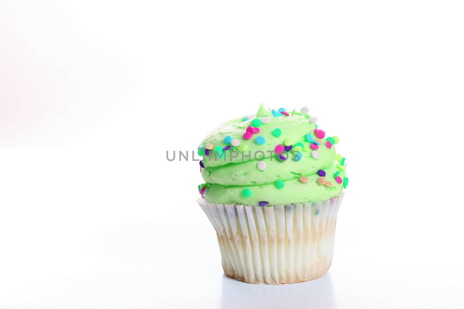 shot of vanilla cupcake with lime green frosting by creativestock