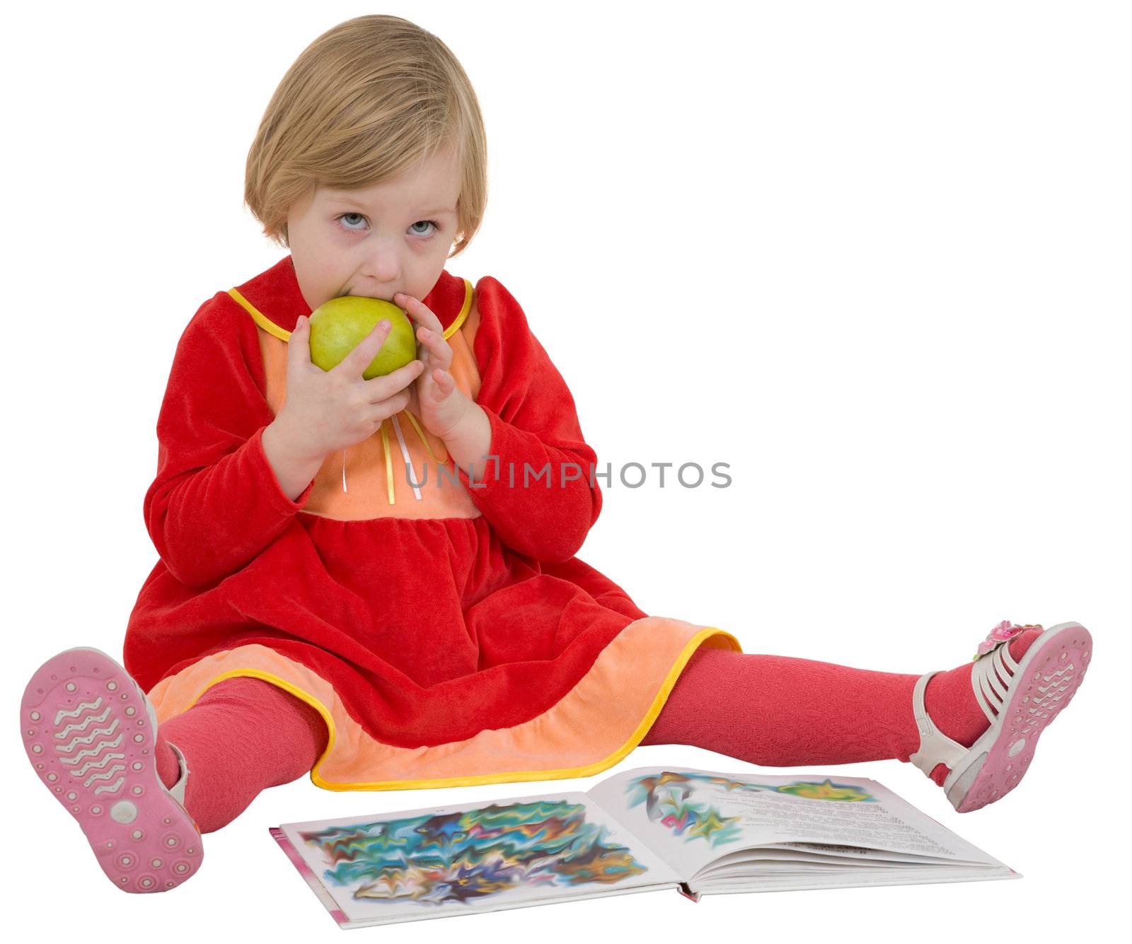 Little girl looking book and eating green apple