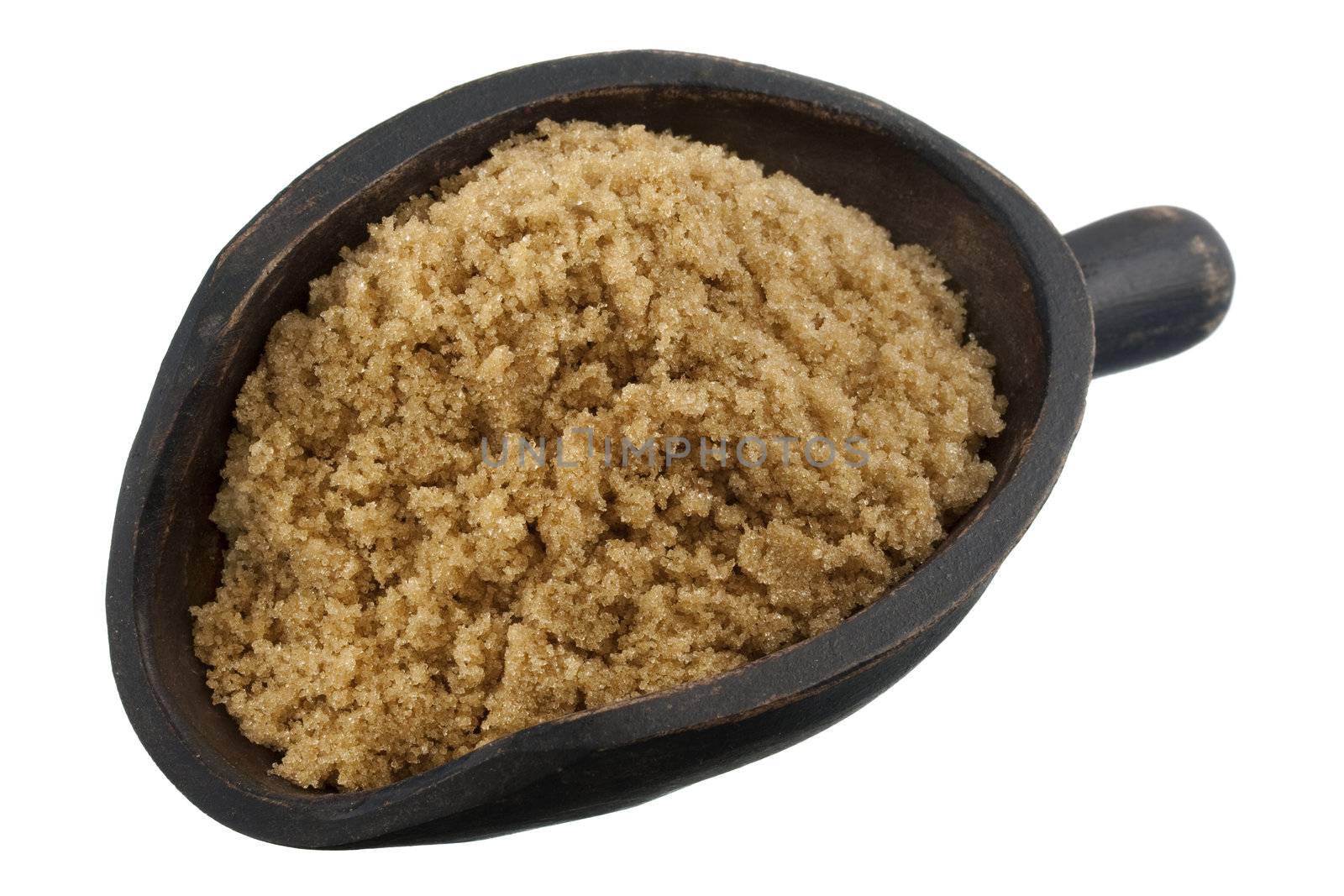 brown cane sugar on a rustic, wooden scoop isolated on white