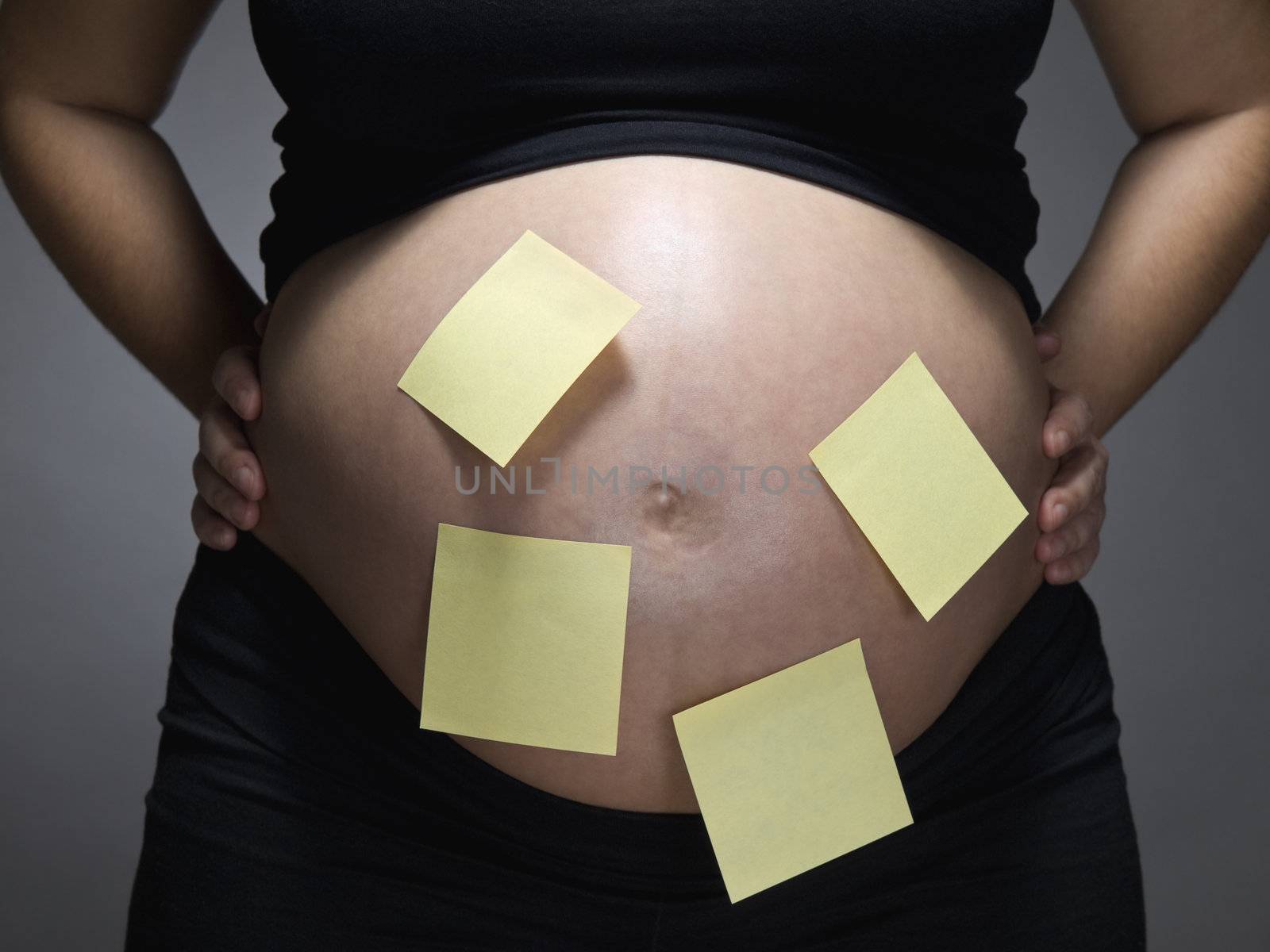 Pregnant woman with blank sticky notes on her belly.
