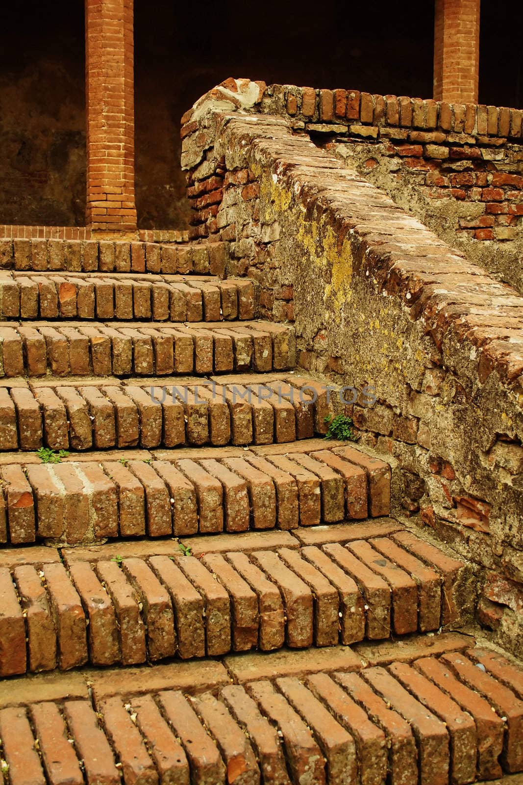 Old brick stairs and columns in Tuscany with moss