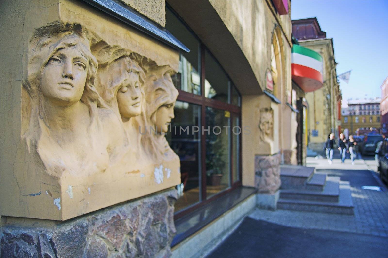 Entrance to cafe in city street with a group of people in background. The building was built before 1900, and the sculptures on the facade are public monuments and nobody can have copyright on them.