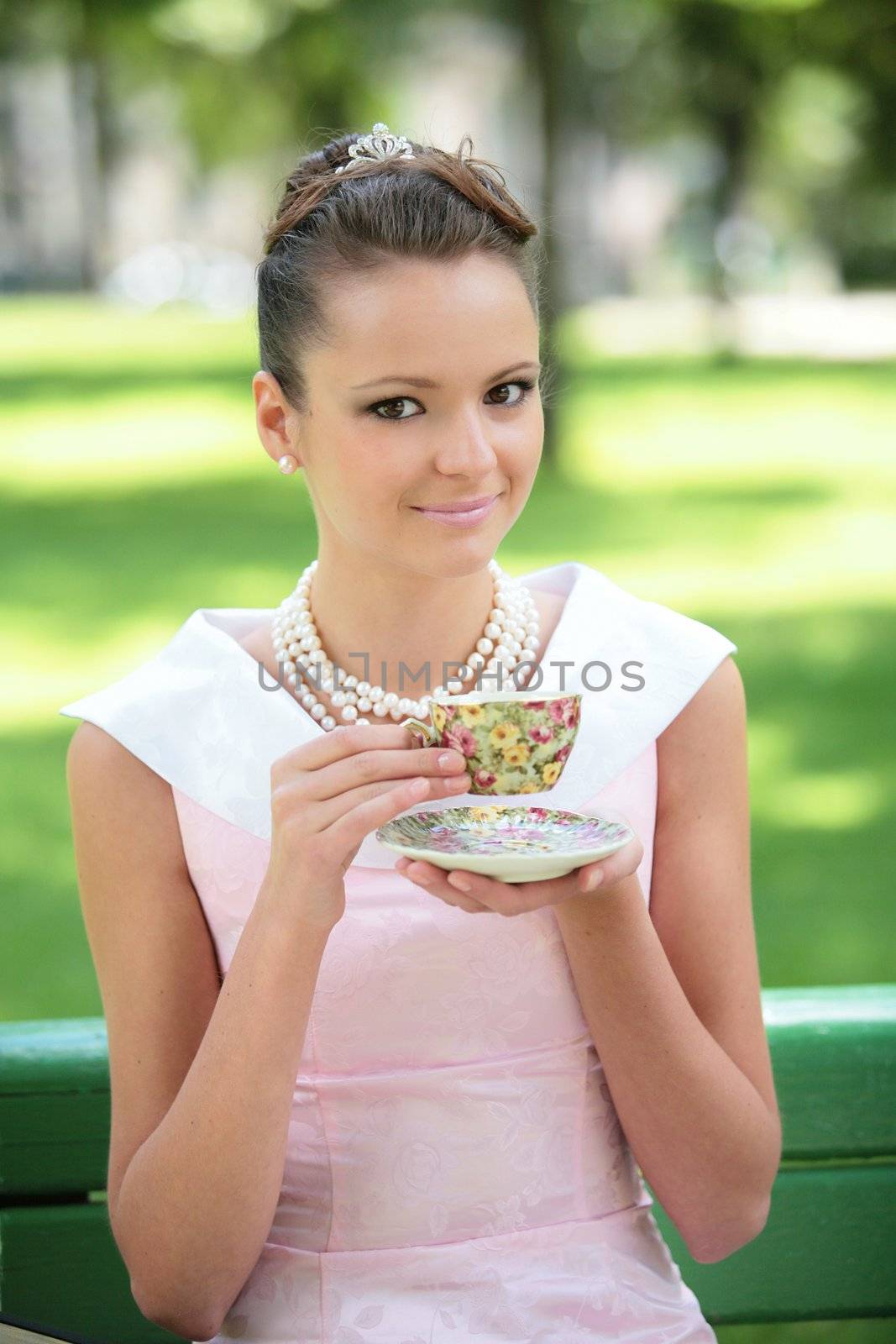 smiling girl in white-rose dress and necklace from pearl drink coffee