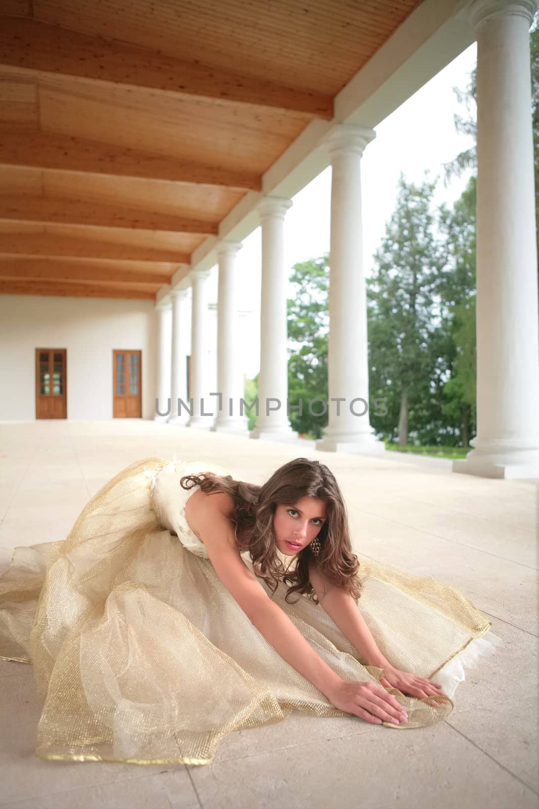 bride in golden gown on floor amongst pillars of the old-time building