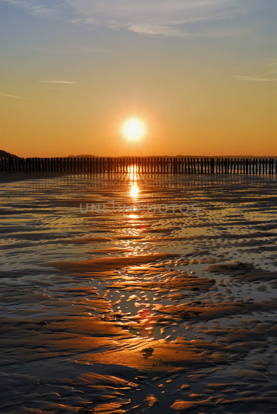 wet empty beach with last sun over it