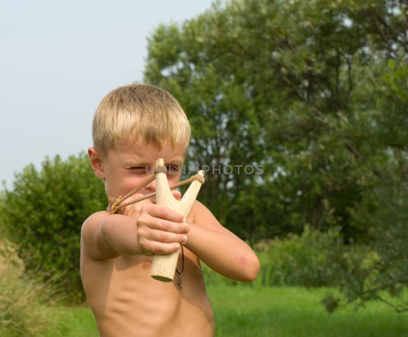 A boy aiming a wooden slingshot.