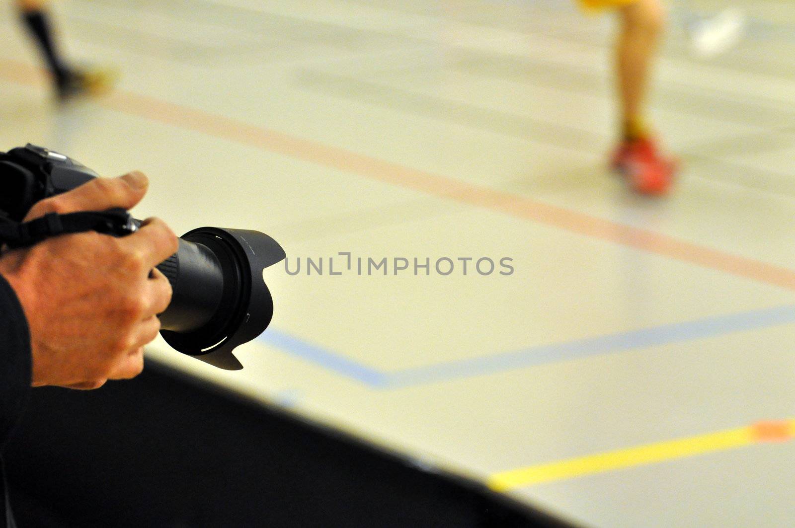 A photographer using his digital slr to capture a match of floorball.