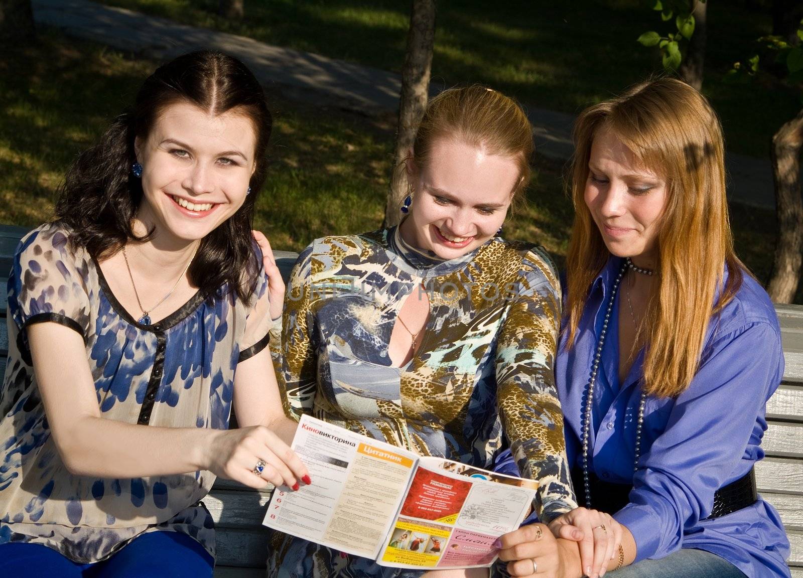 Three girls discuss magazine on the branch by palomnik