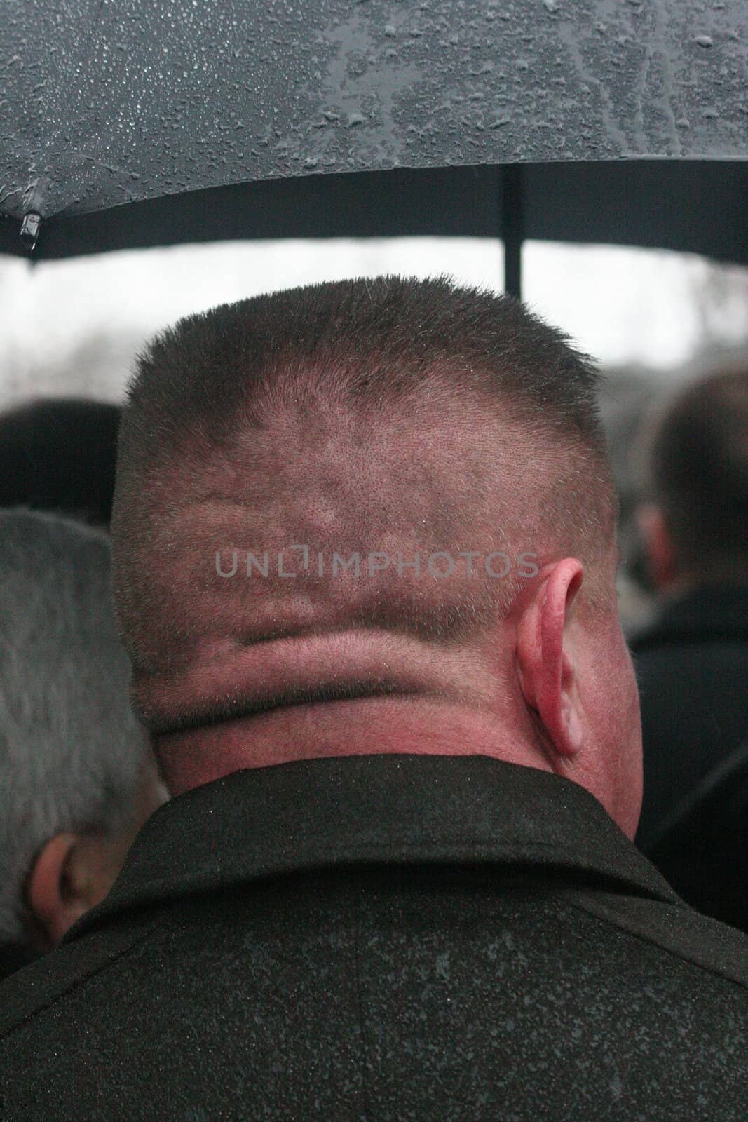 The man with a short hairstyle revolved by a nape to the chamber costs{stands} under a umbrella{parasol} during a rain largly Kharkov Ukraine 19 01 2007