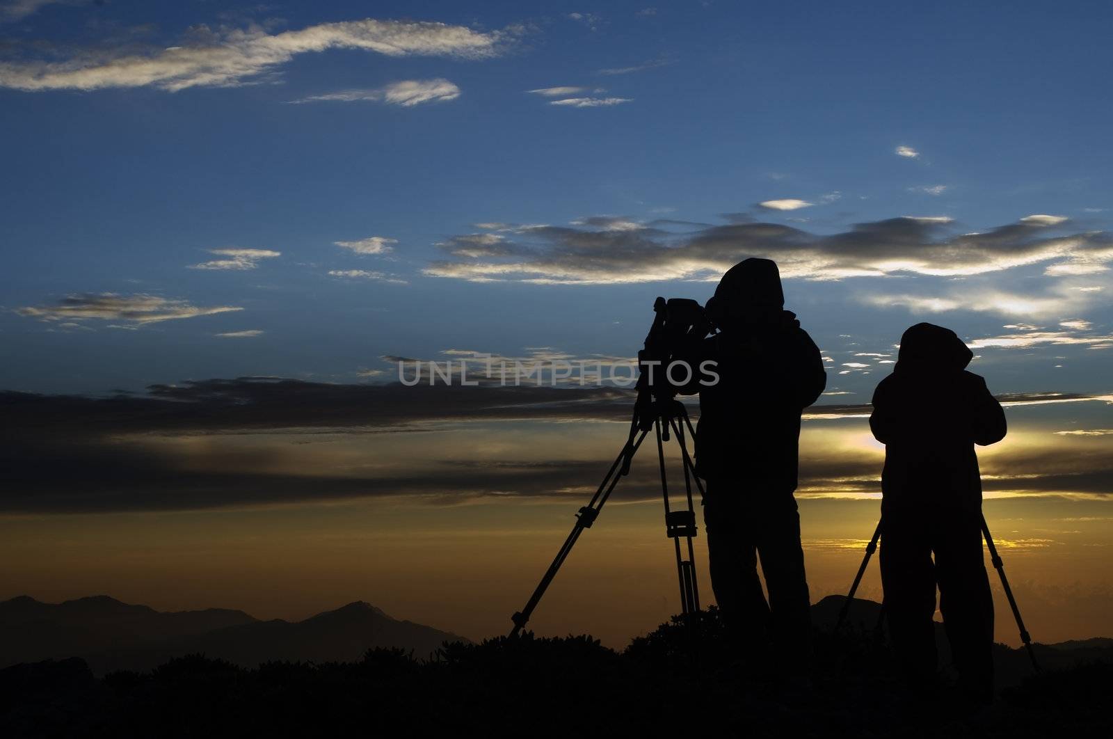 A couple of photophers in the morning sunrise.That's true love to take picture in cold morning!