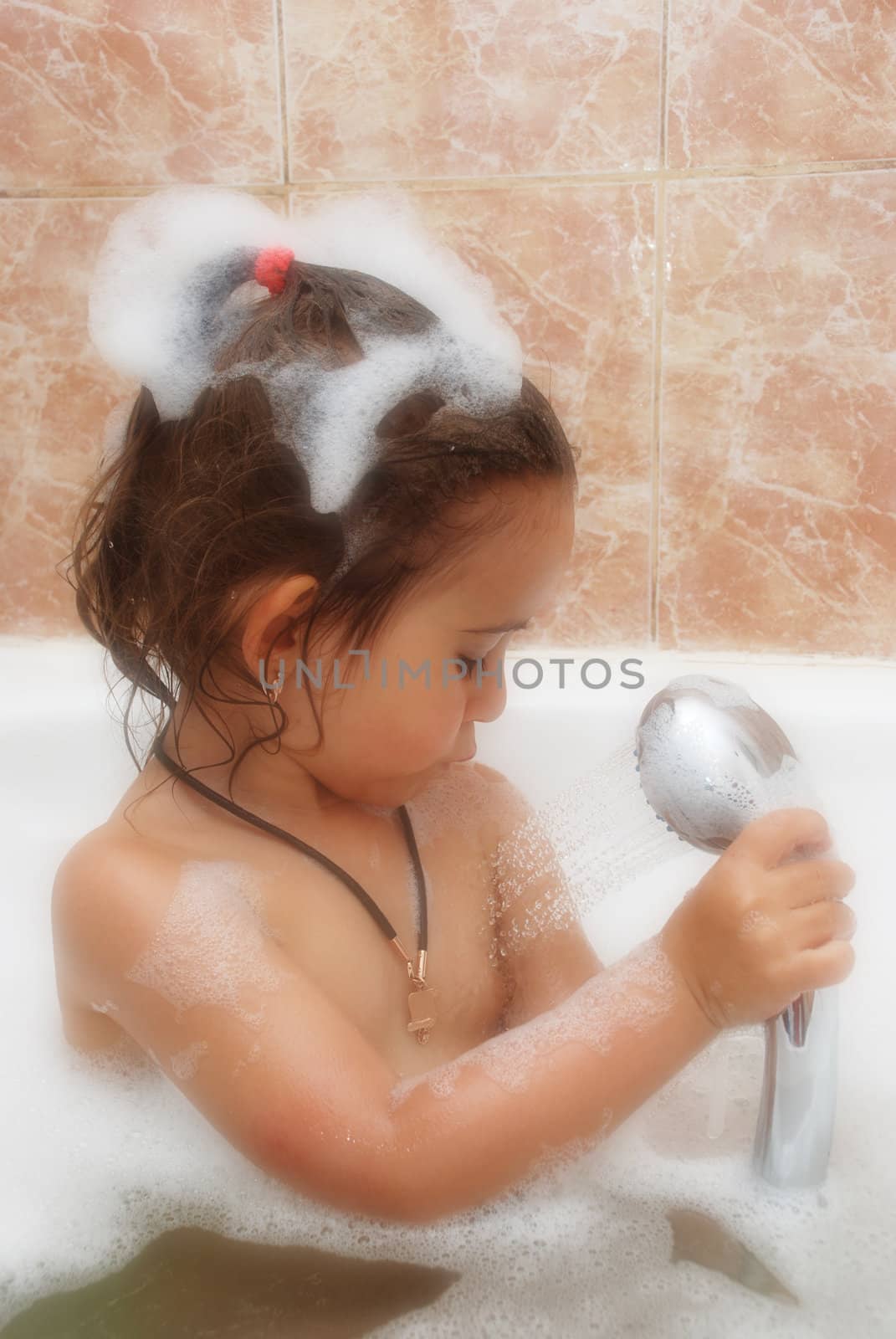 little girl take a bath. Fluffy foam round its body and on her head.