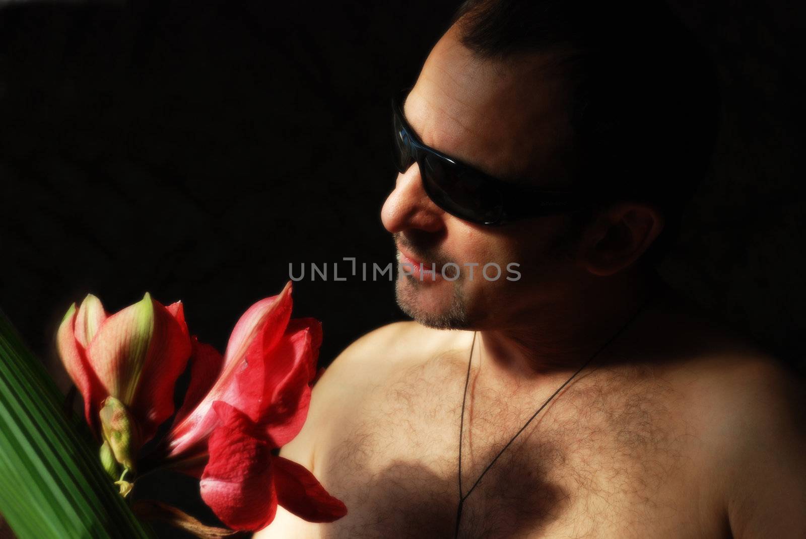 The fashionable man in sunglasses with a huge red flower
