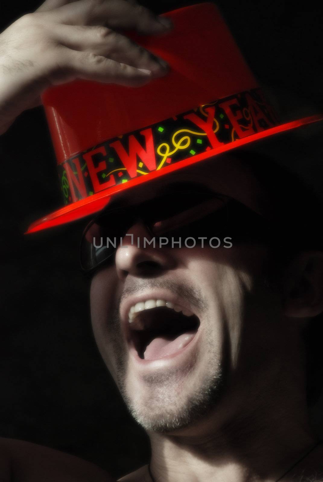 The fashionable man in a red hat with an inscription "Happy New Year" joyfully shouts