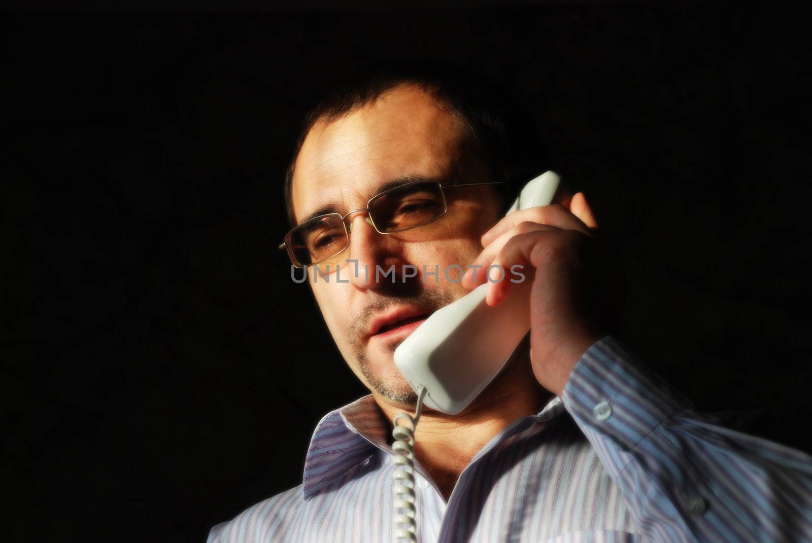 The businessman in a white shirt with stripes speaks by phone