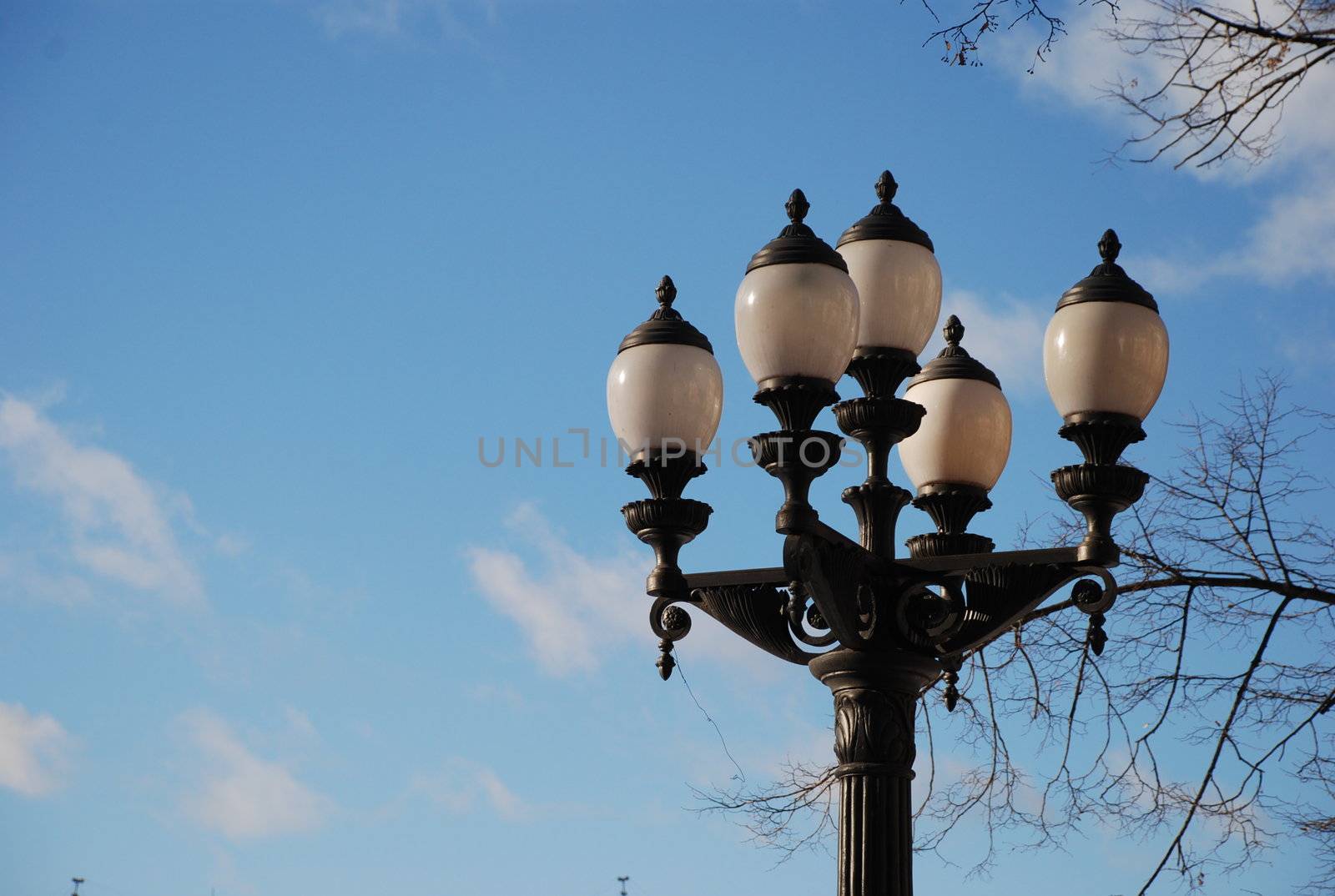 white streetlight on black metal lamppost, blue sky and white clouds