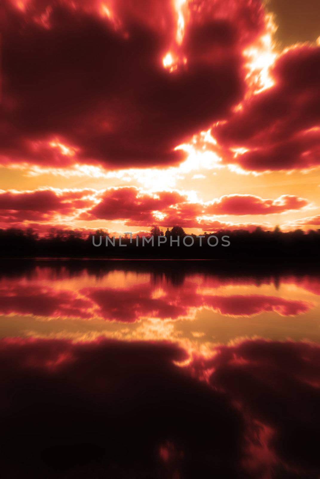 Sunset over lake in a city. The big clouds are reflected in water