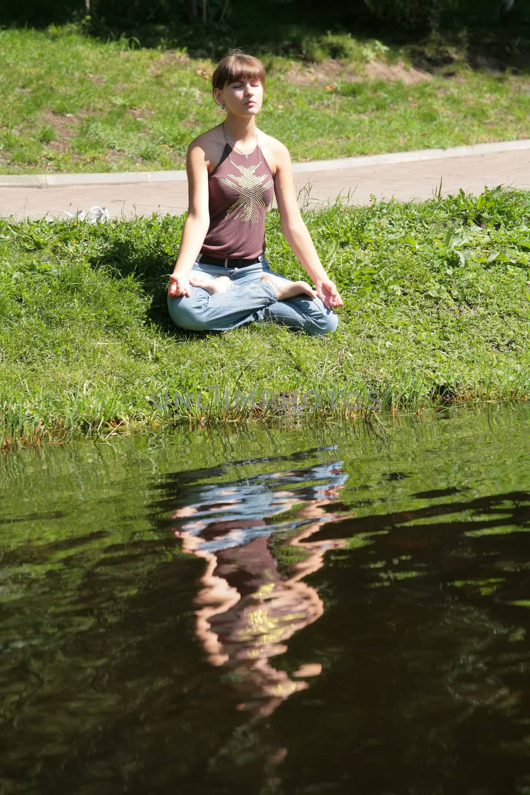 beautiful girl meditating near by water with reflections