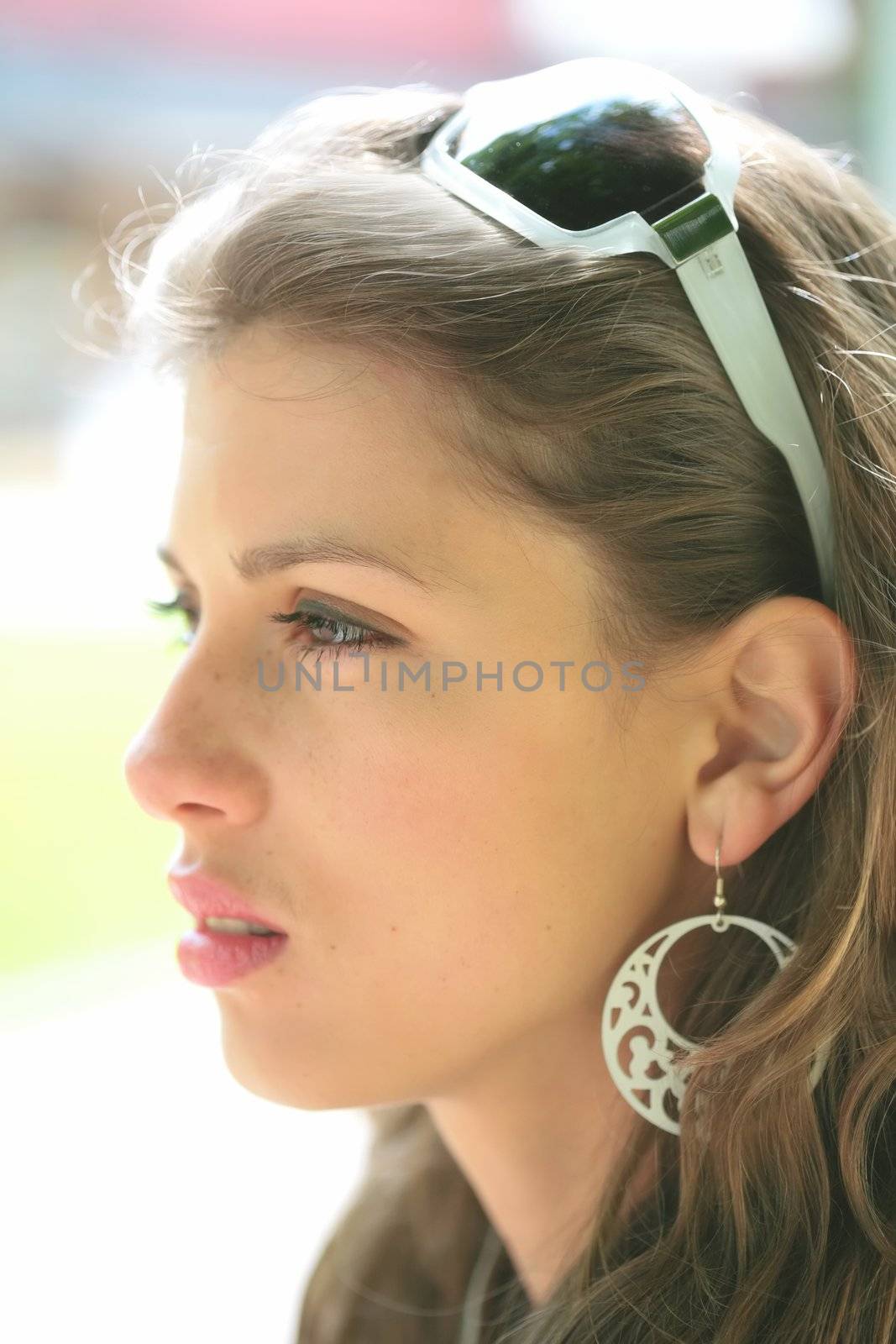 close-up portrait of the young beautiful woman with silver earring and sunglasses, profile