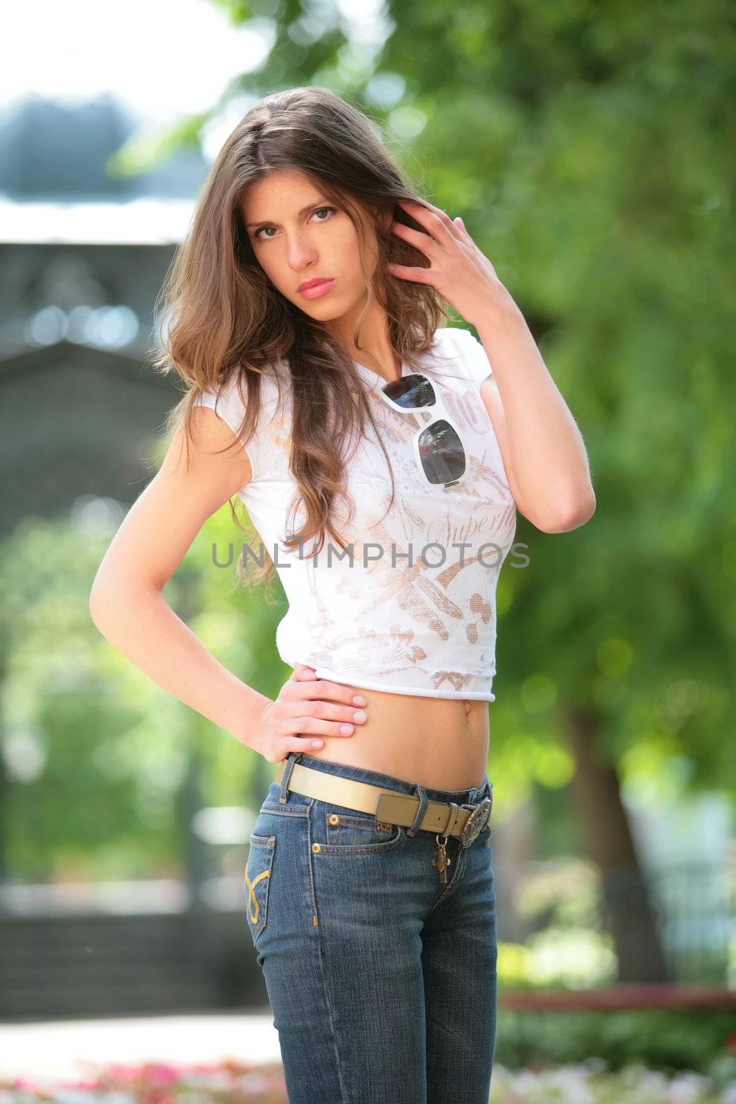 very serious beautiful girl in light t-shirt and jeans corrects hairs