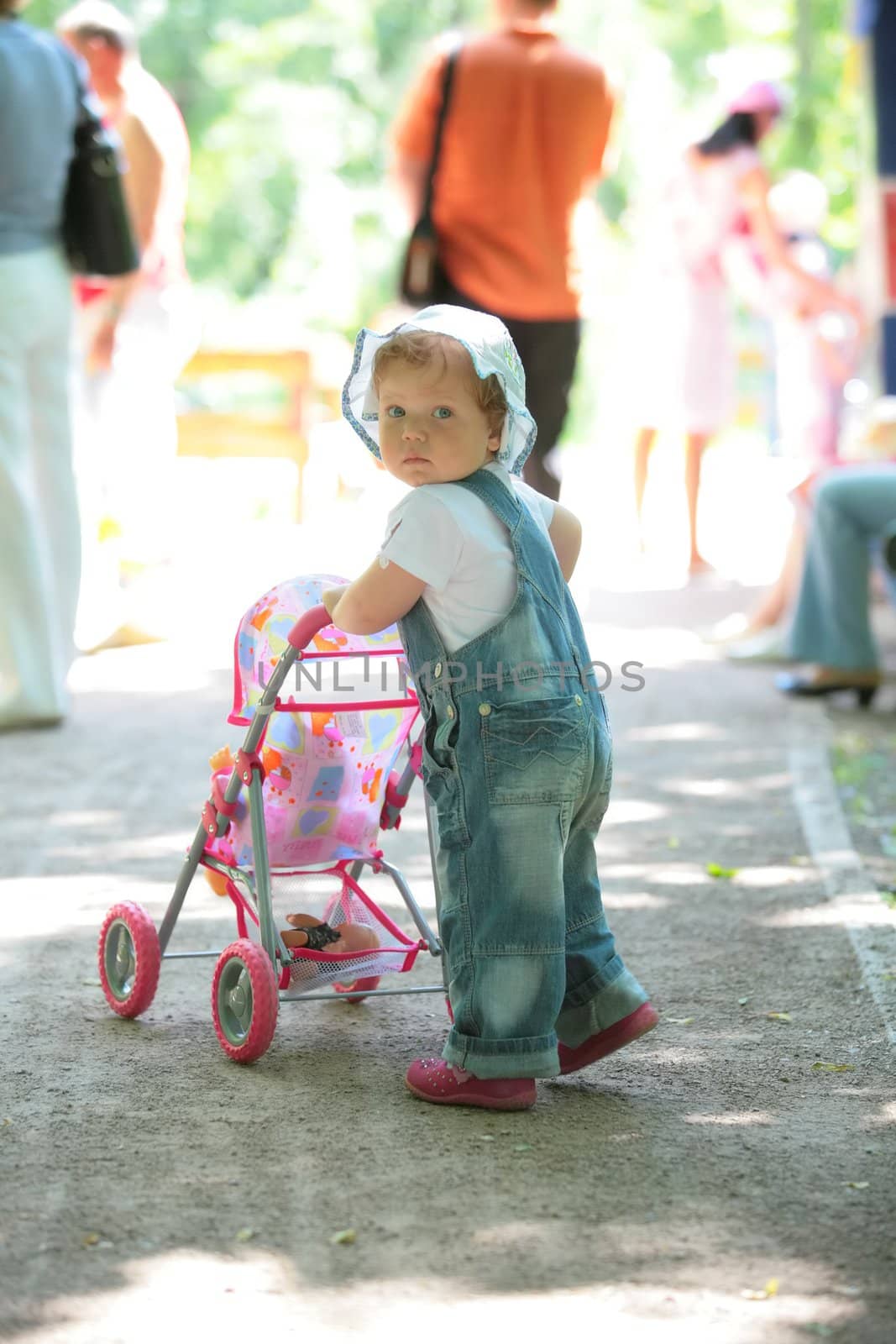 little girl walks in park with doll in sidercar