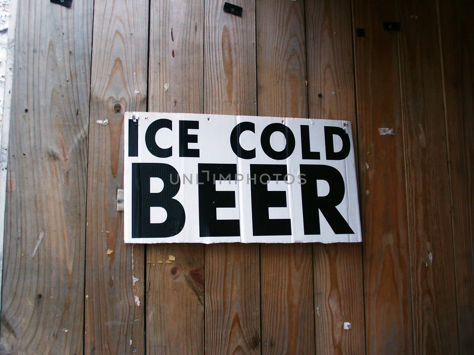 An "Ice Cold Beer" sign hanging on a wooden wall.