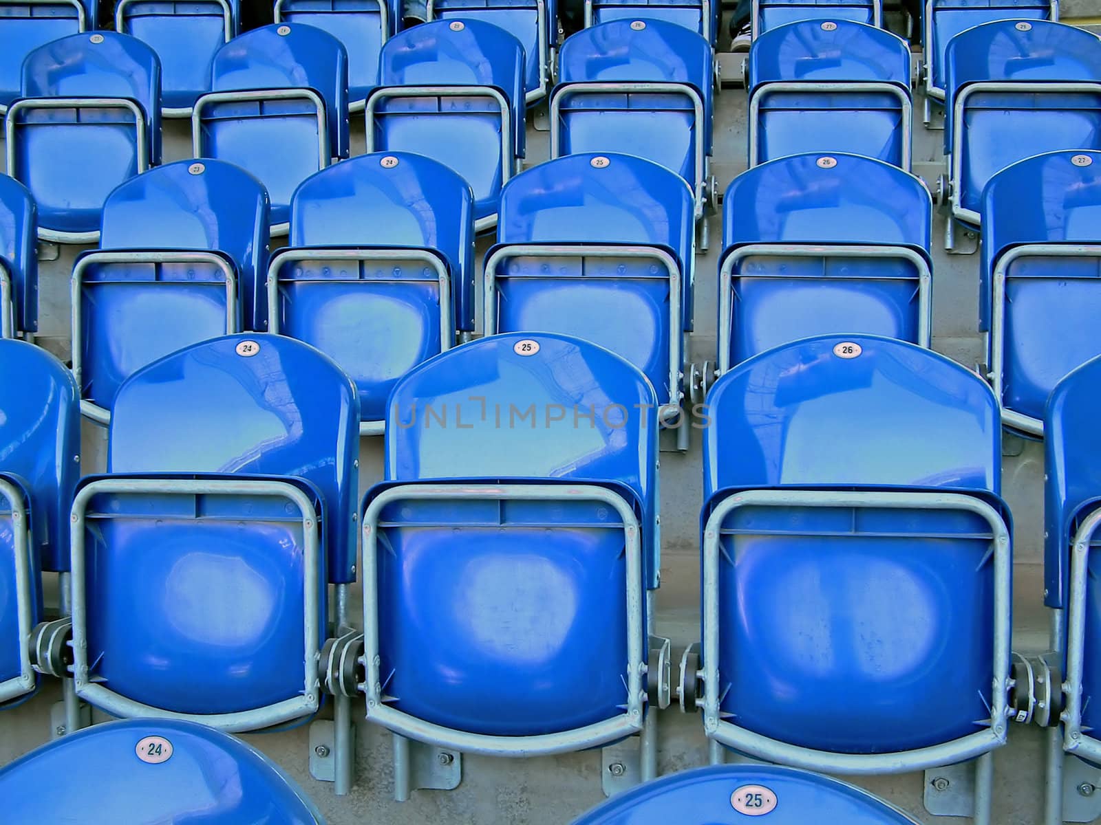 Photographic image of plastic folding chairs on sports arena.