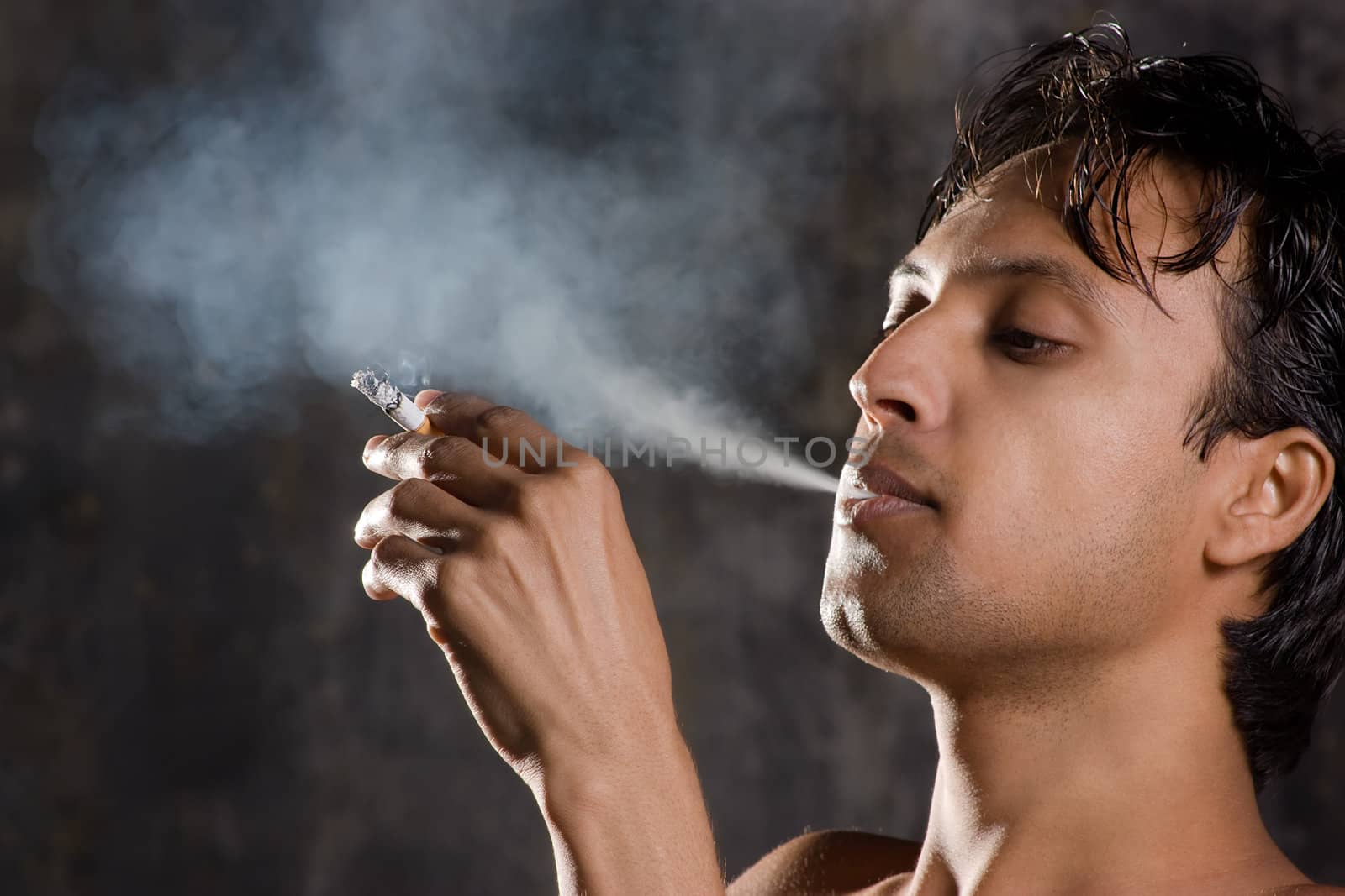 Close-up of an intensively smoking man with heavy smoke 