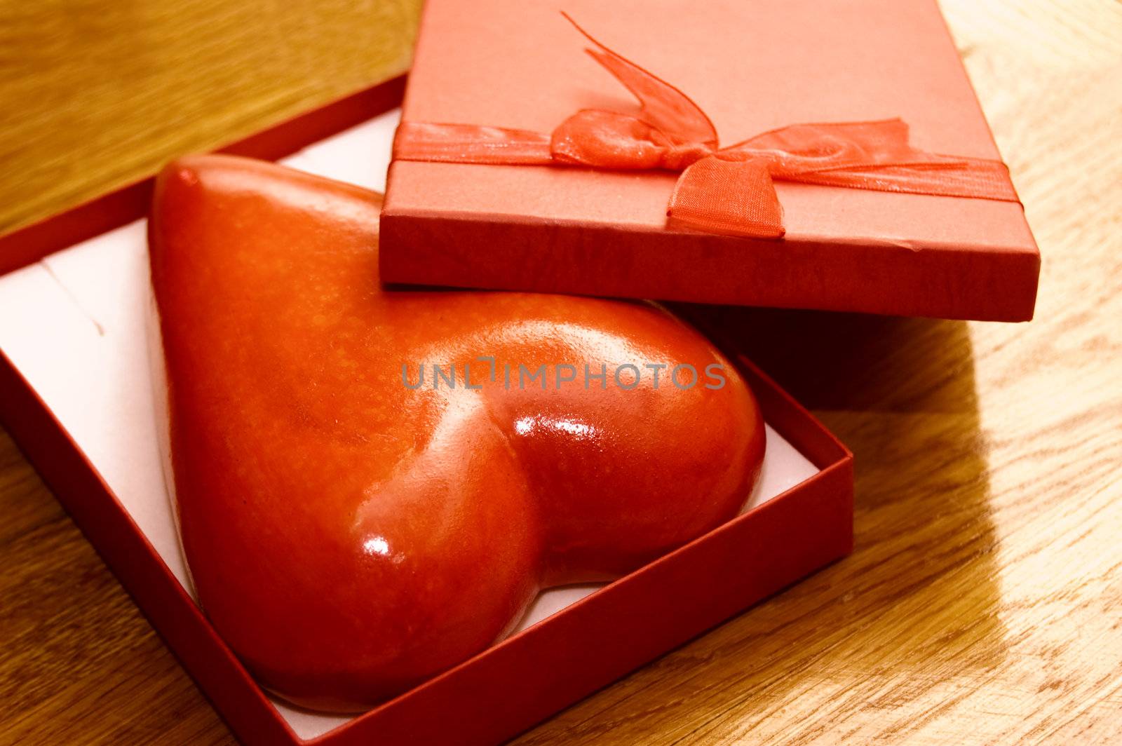 Heart in gift box over wooden background