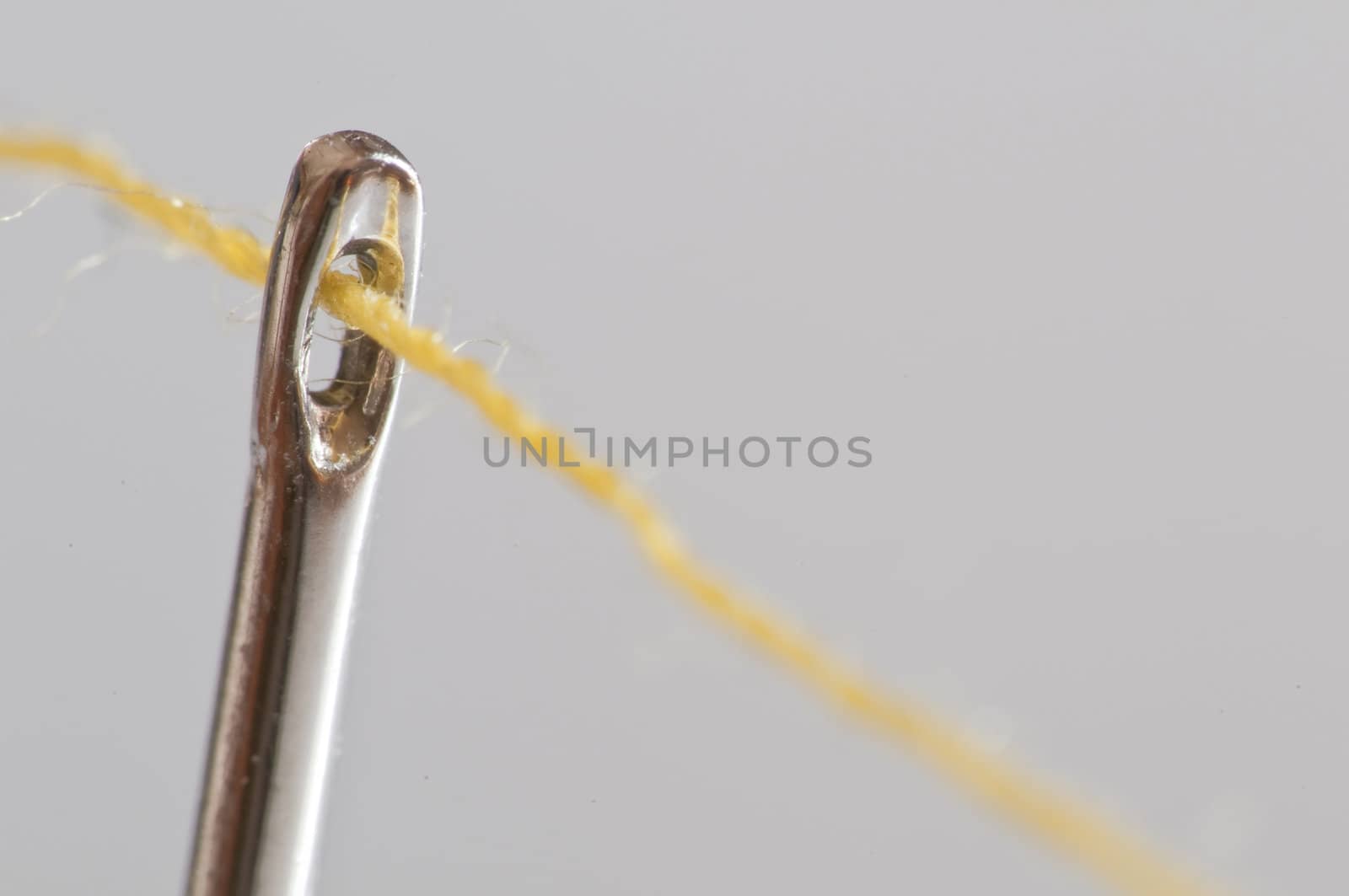 yellow cotton thread through a needle eye