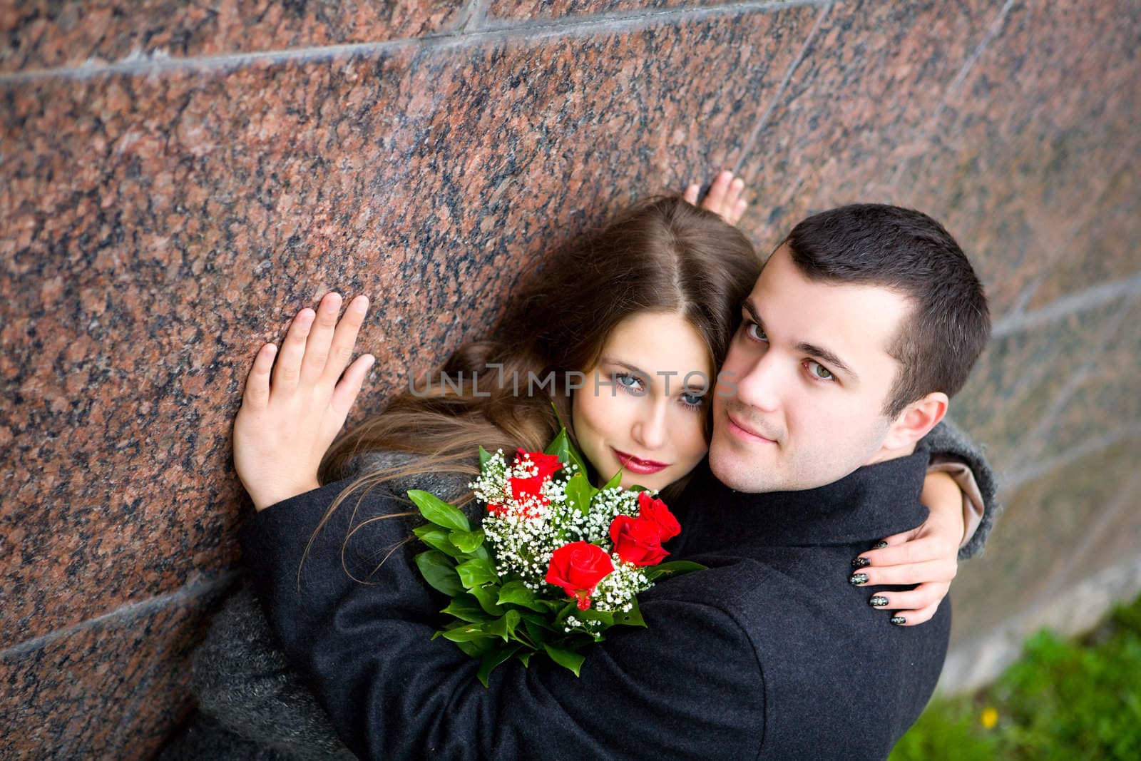 Two young lovers looking at you at granite wall