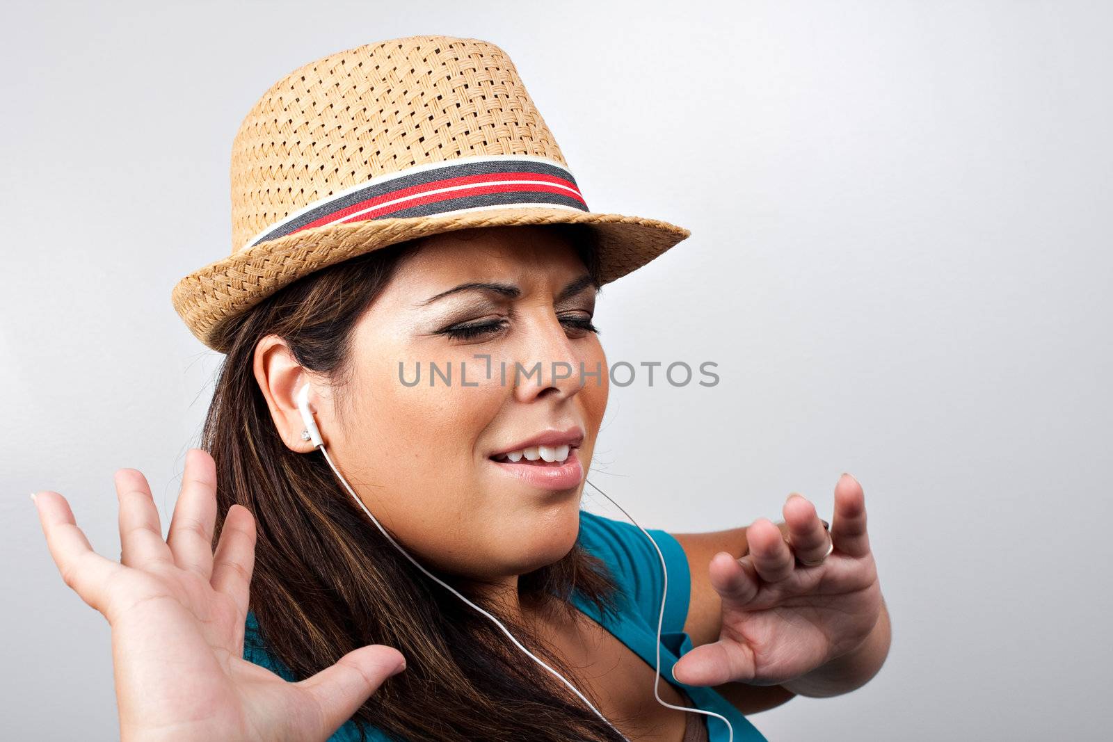 An attractive Hispanic woman listening to and getting into the music playing through her stereo ear bud headphones. 