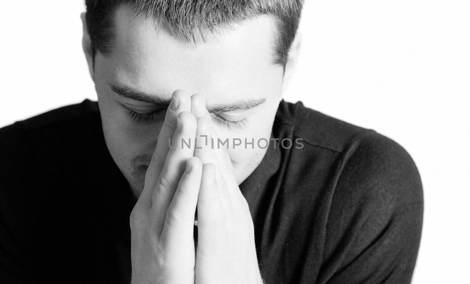 Young man praying with eyes closed closeup isolated on white
