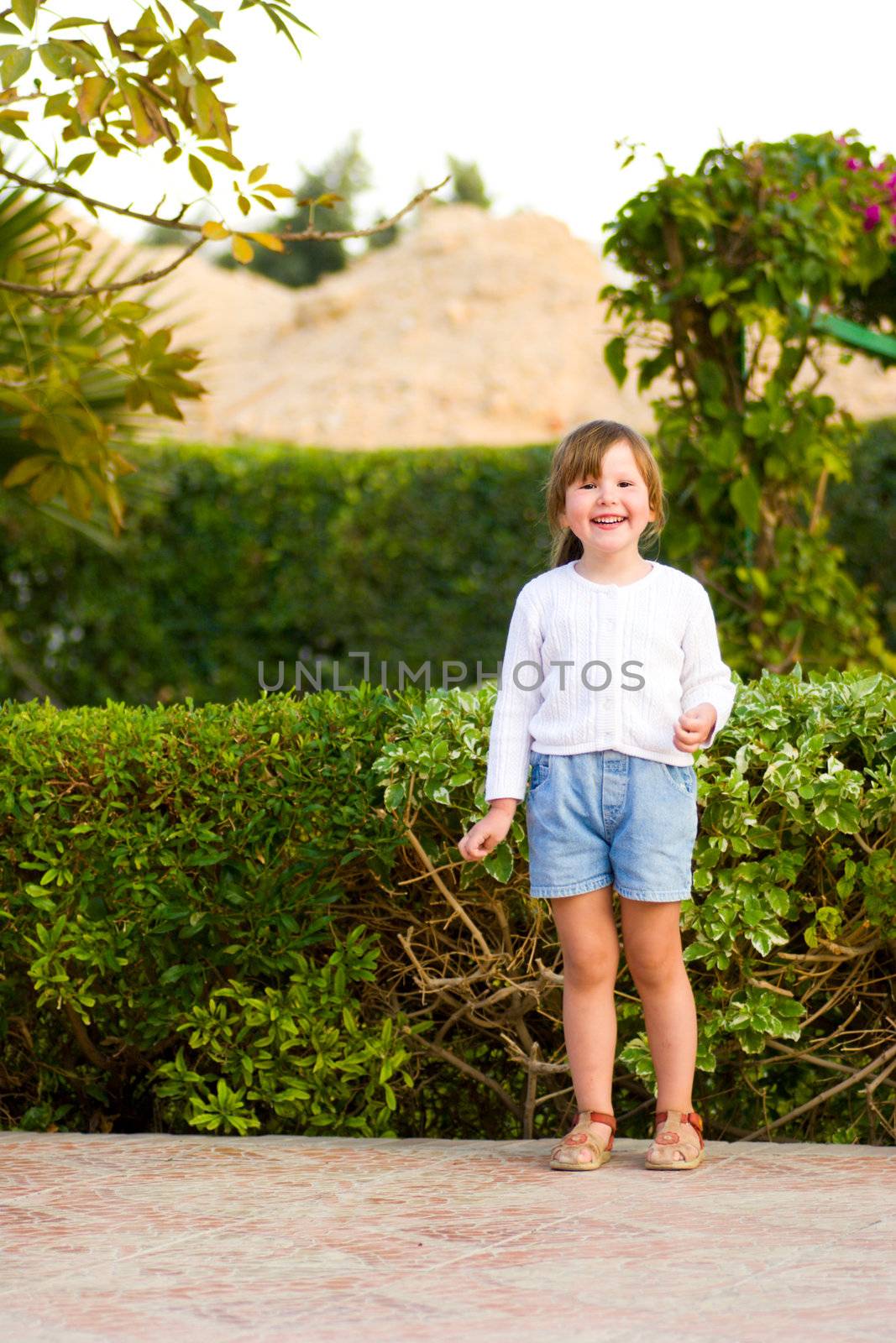 Happy little girl standing in backyard laughing