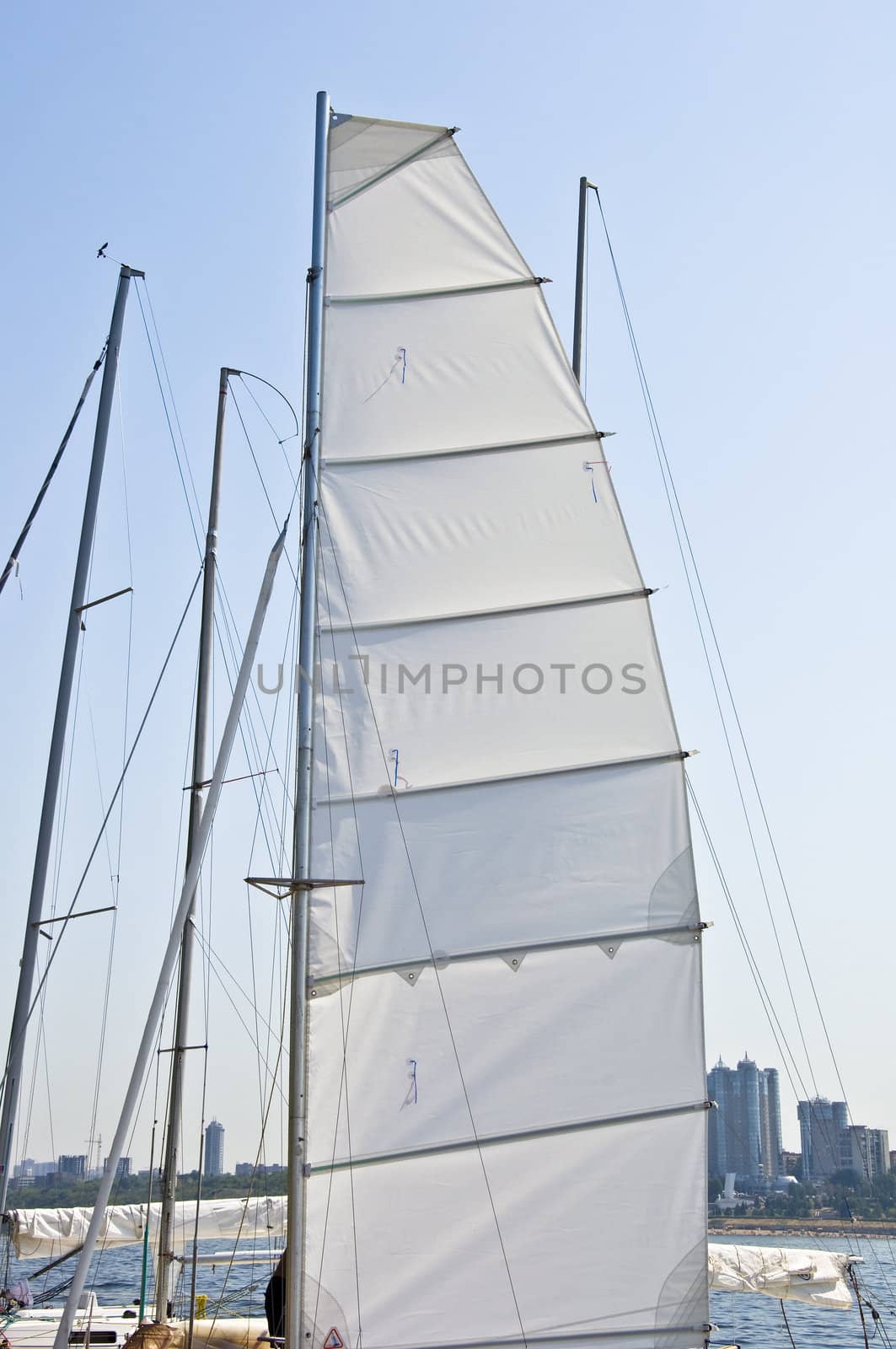 Mast yacht with a sail. Against the backdrop of the river and a major port city in Russia.