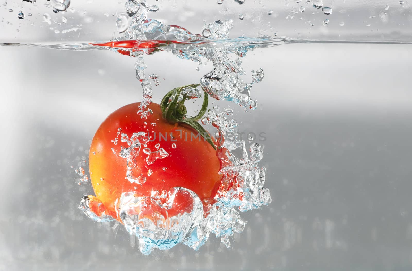 A cherry tomatoe dip into water