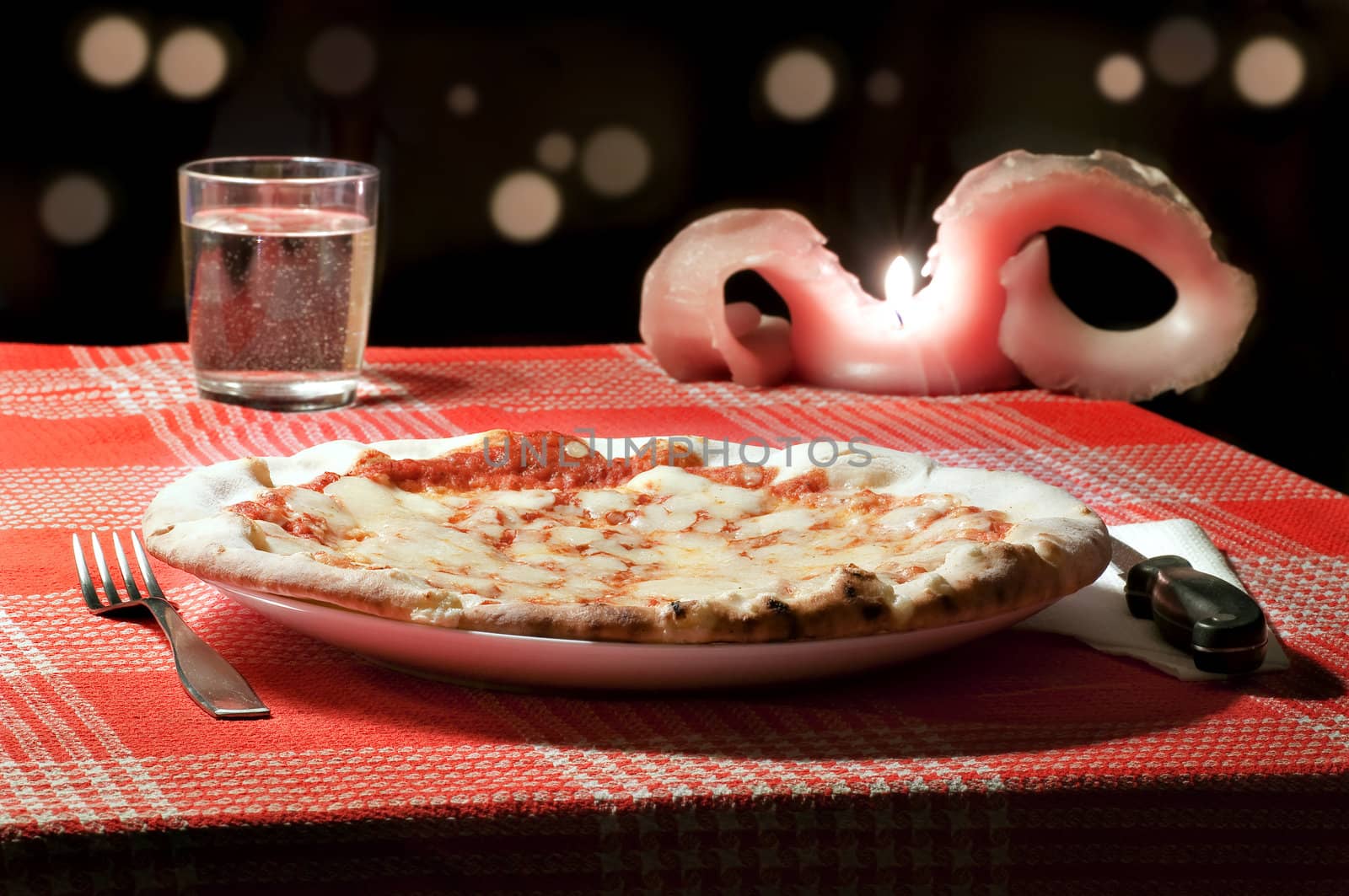 A margherita pizza on a table of a romantic pizzeria