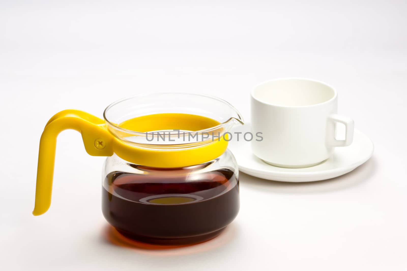 A transparent teacup with yellow handle and black herbal tea  white cup