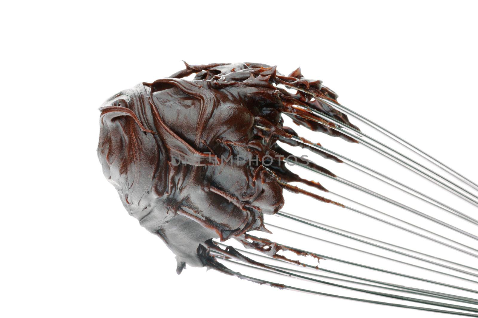 A whisk with chocolate frosting isolated on a white background.