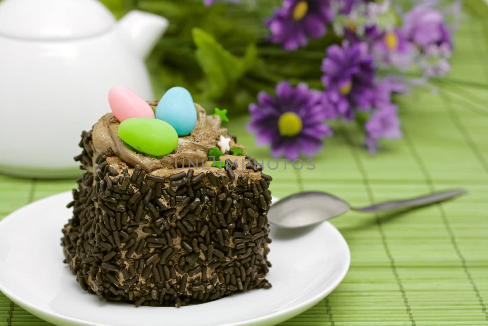 Colorful sweet eggs on a chocolate cake nest with sprinkles to celebrate spring or Easter