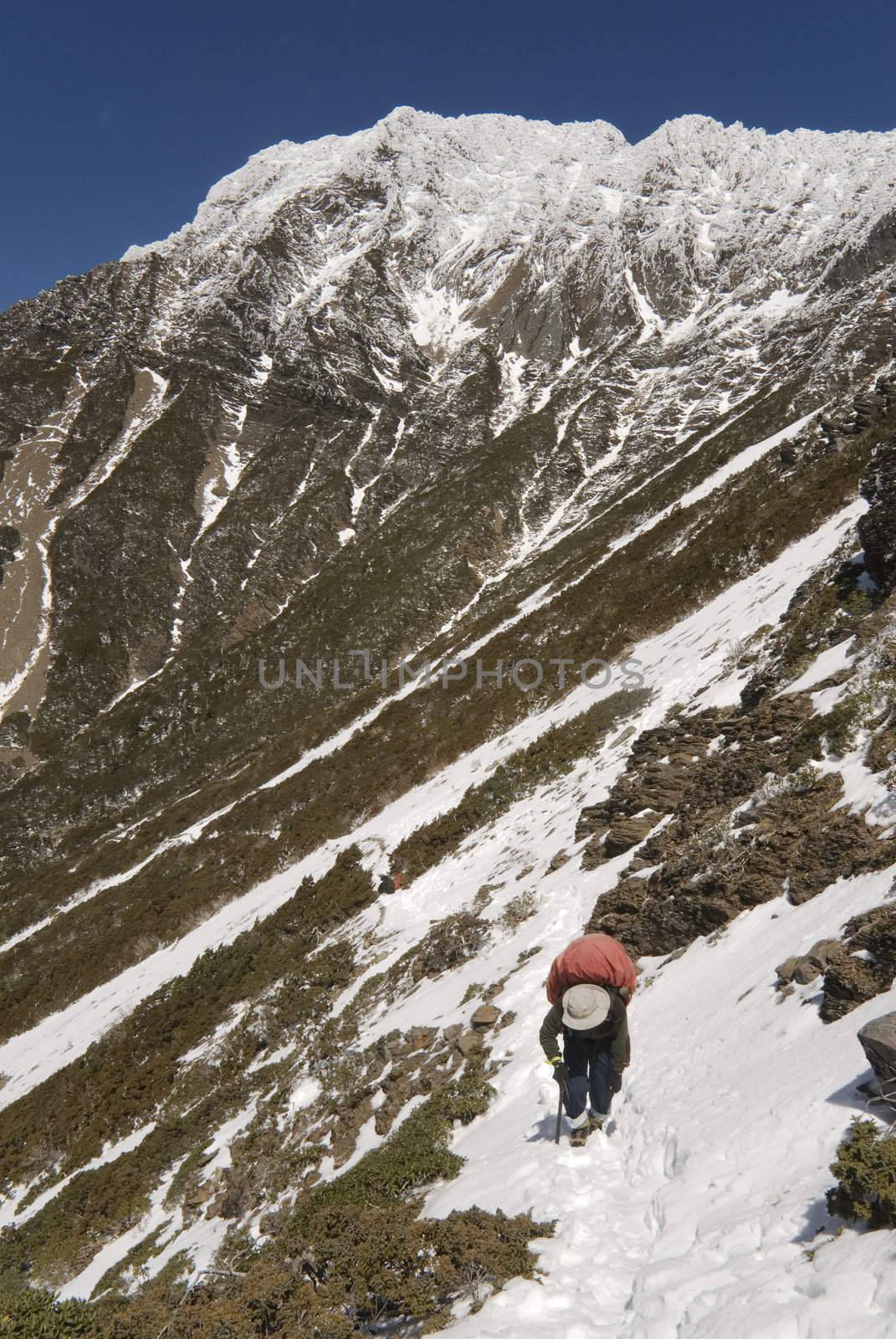 A man walk on snow, background was the highest mountain of eastsouth Asia.