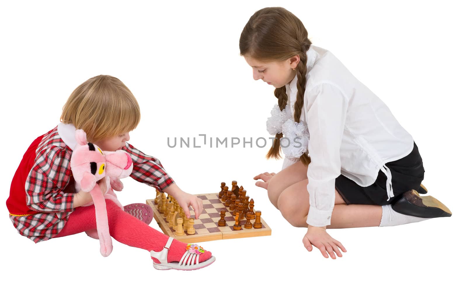 Girl teaching little girl play chess on white