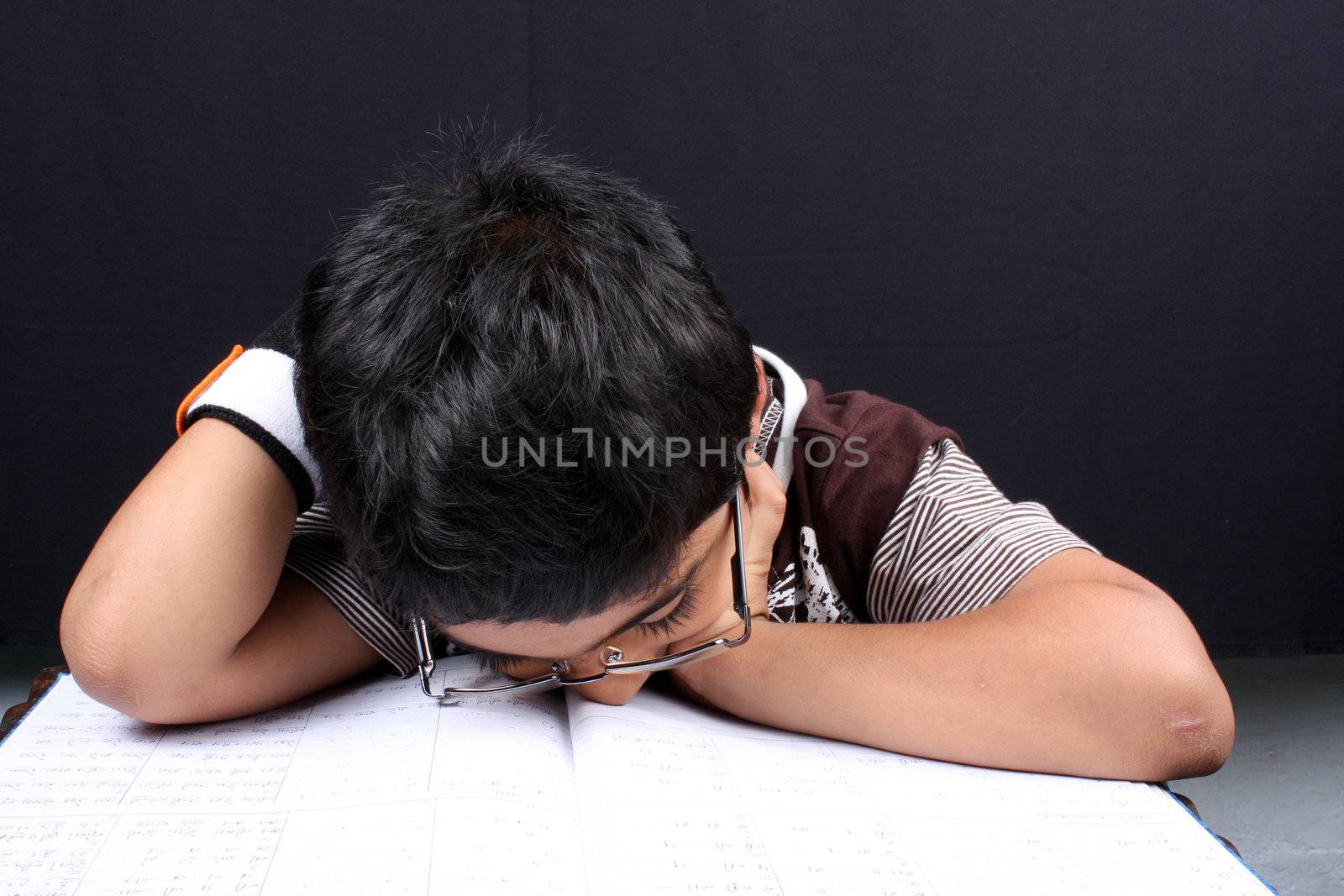 A little boy fallen asleep after tired of studying.