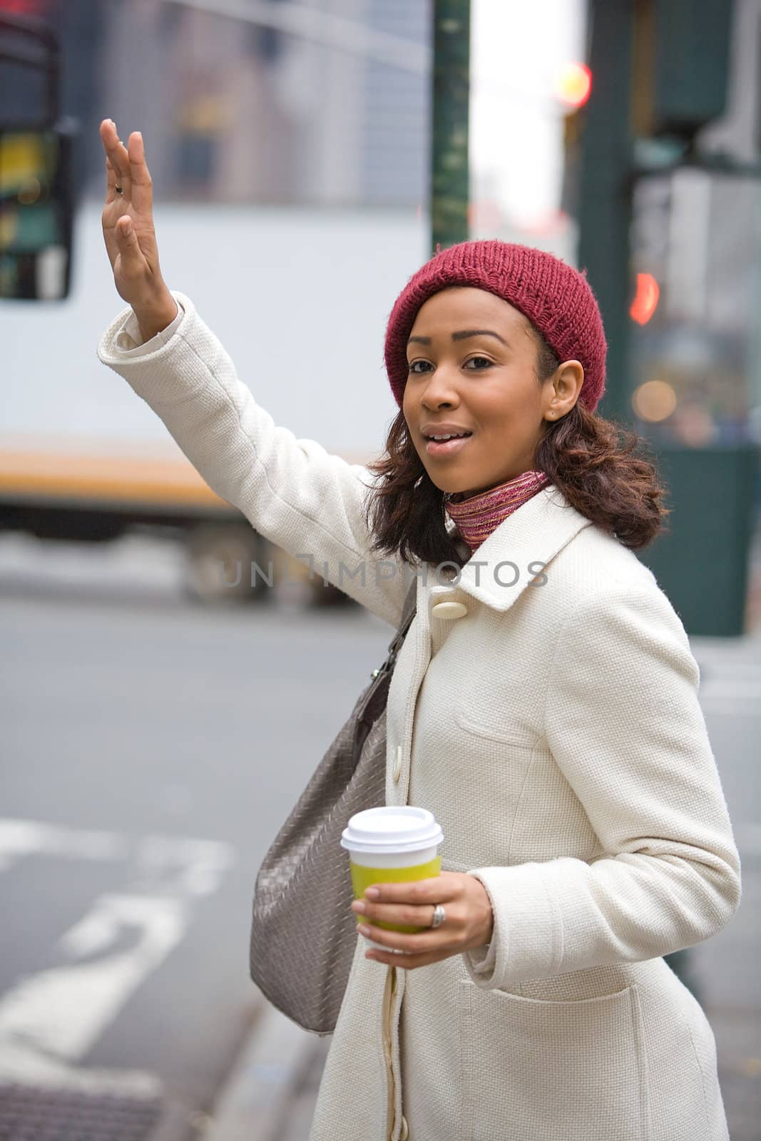 A pretty young business woman hails a taxi cab in the city.