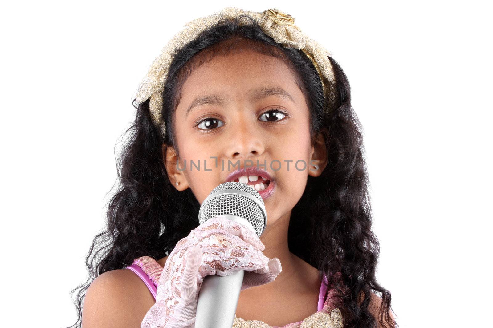 A portrait of a cute little Indian girl making a speech, holding a mic on white studio background.