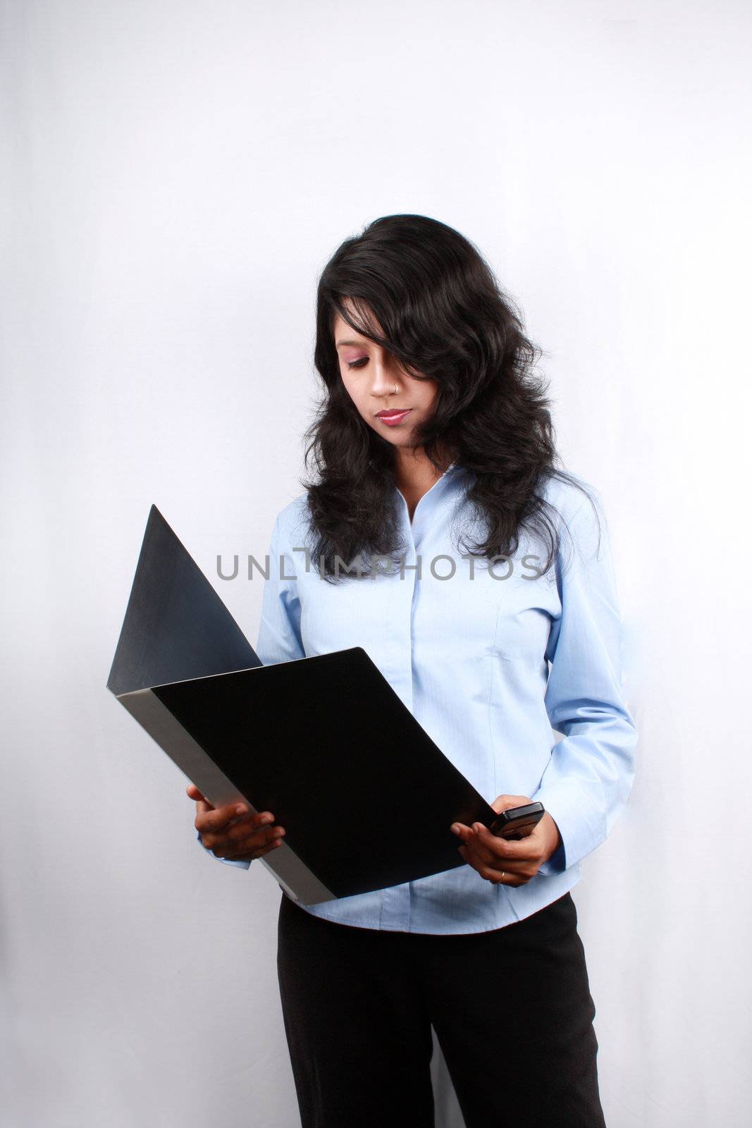 A young Indian businesswoman reading documents in a file.