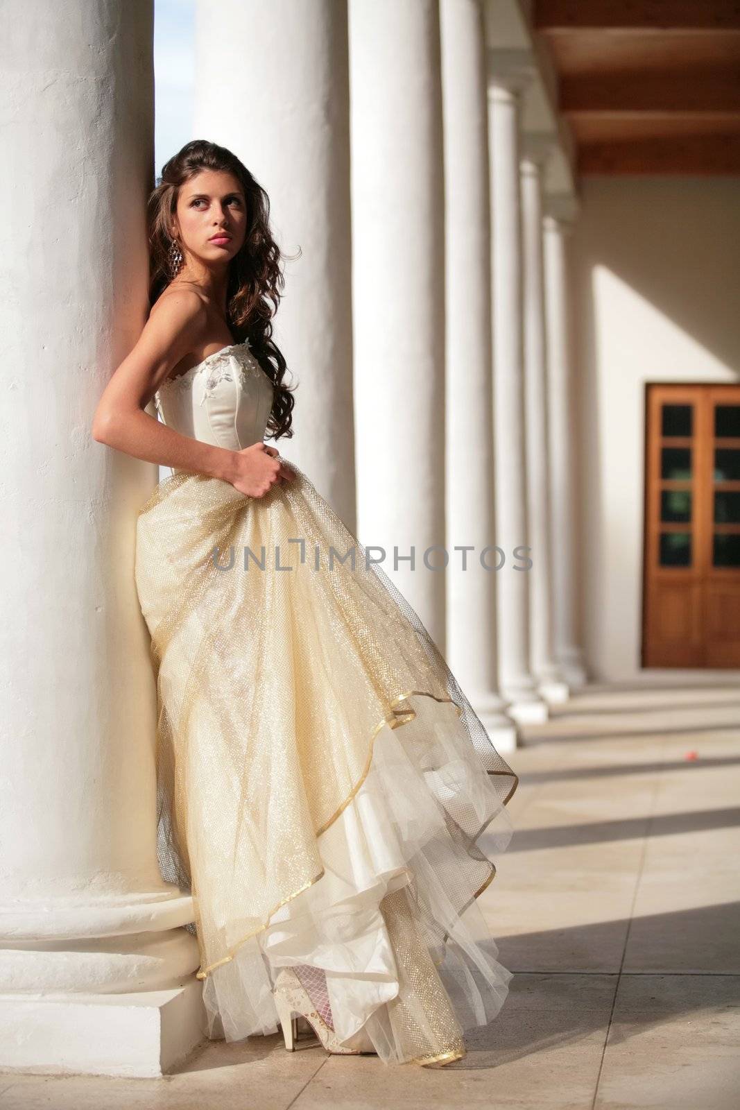 girl in golden gown amongst pillars of the old-time building