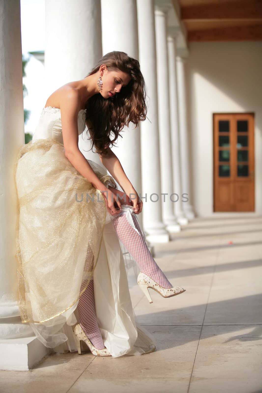 girl in golden gown of the bride corrects stocking